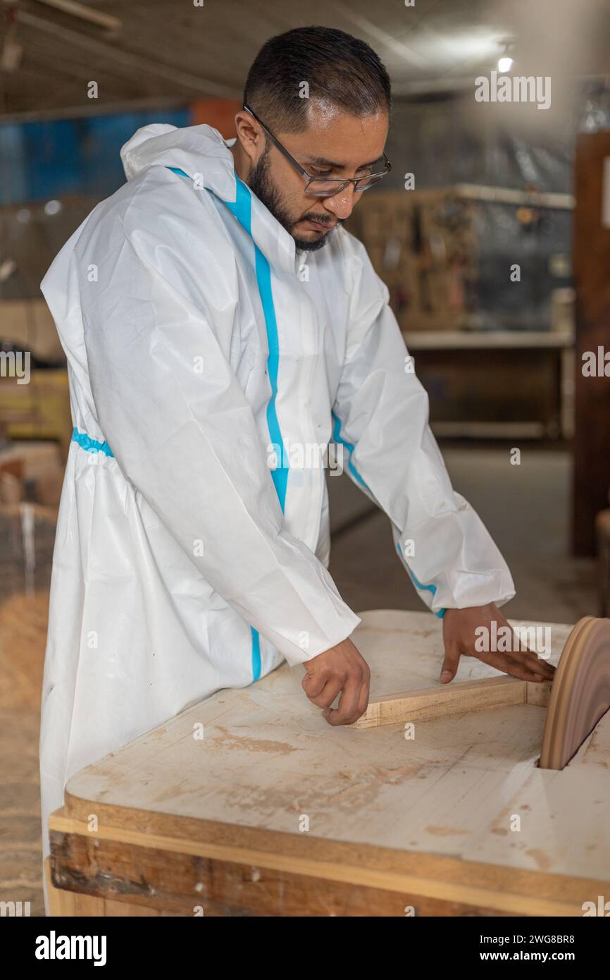 man in overalls inside carpentry shop working with machines and lifestyle, professional and industrial occupation, sanding wood to build handmade Stock Photo