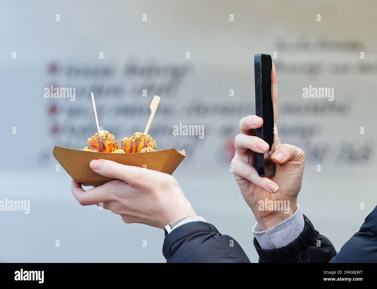 Womans hands holding dessert and mobile phone, midsection of womans body taking selfie of dessert with copy space, farmers street food market at Pragu Stock Photo