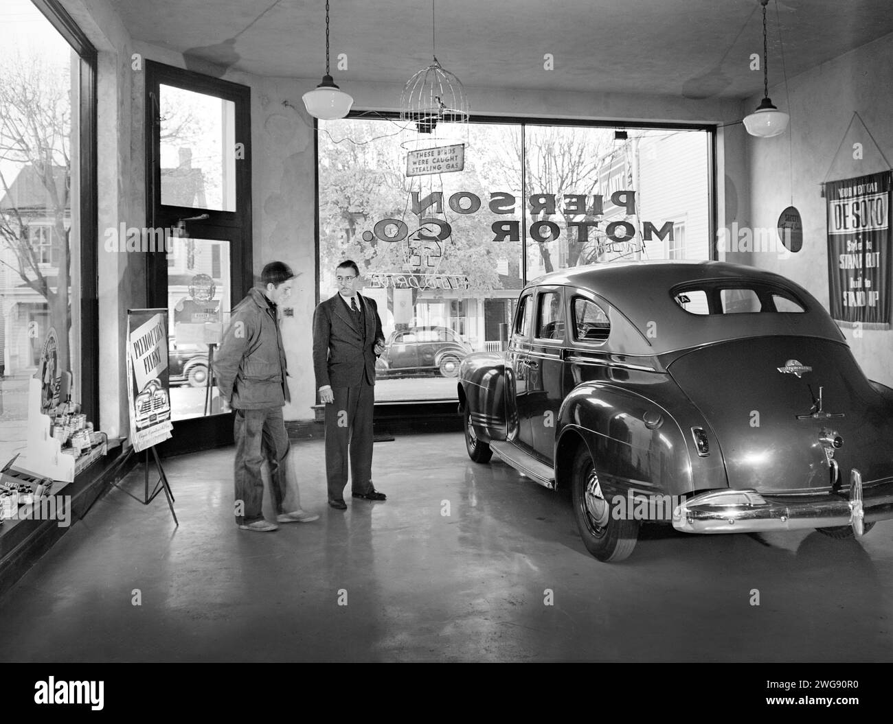 Pierson Motor Company showroom owned by Al Pierson (right) who is showing his one second-hand car to local farmer. Before World War II there always were three brand new cars in his showroom, now during the war, the chief business is repairing, Lititz, Pennsylvania, USA, Marjory Collins, U.S. Office of War Information, November 1942 Stock Photo