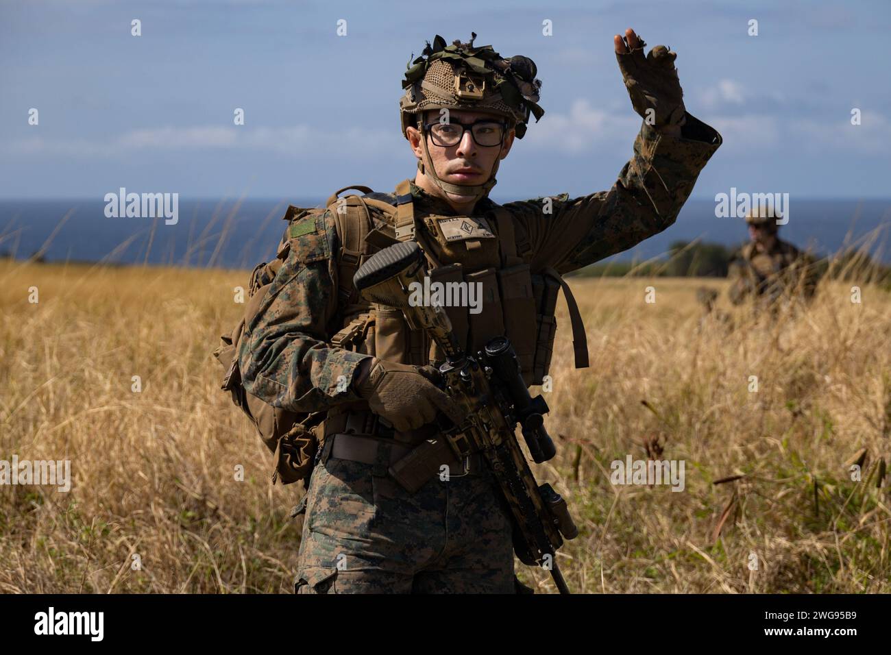 U.S. Marine Corps Lance Cpl. Aaron Coats, an infantry Marine with Battalion Landing Team 1/1, 31st Marine Expeditionary Unit, executes a hand signal while on a patrol during a helicopter raid exercise at Ie Shima, Okinawa, Japan, Feb. 2, 2024. The exercise simulated taking control of an enemy airfield and supporting further denial operations. The 31st MEU is operating aboard ships of USS America Amphibious Ready Group in the 7th fleet area of operations to enhance interoperability with allies and partners and serve as a ready response force to defend peace and stability in the Indo-Pacific reg Stock Photo