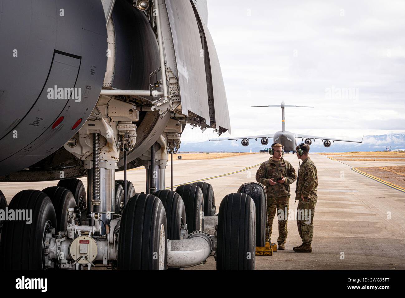 U.S. Air Force Senior Airman Logan Buhk, left, and Senior Airman Joseph Szutyanyi, electrical and environmental systems maintainers with the 22nd Airlift Squadron, preform preflight checks on a C-5M Super Galaxy during Winter Training for the Advanced Airlift Tactics Training Center, at Fort Huachuca, Arizona, January 24, 2024. Winter Training is a break from the regular course schedule where the instructors of AATTC tweak the training scenarios for the coming year and perform them, with the help of guest units, to keep their skills fresh. This is the first time that a C-5 has practiced tactic Stock Photo
