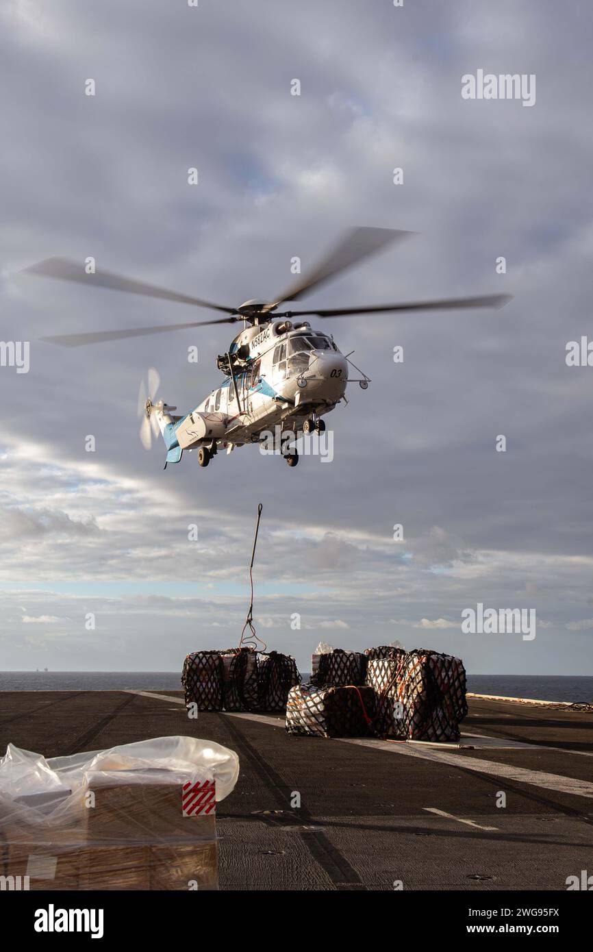 PACIFIC OCEAN (Jan. 28, 2024) – An AS-332 Super Puma, assigned to the Military Sealift Command dry cargo and ammunition ship USNS Charles Drew (T-AKE 10), delivers supplies on the flight deck of the Nimitz-class aircraft carrier USS Theodore Roosevelt (CVN 71) during a replenishment-at-sea, Jan. 28, 2024. An integral part of U.S. Pacific Fleet, U.S. 7th Fleet operates naval forces in the Indo-Pacific and provides the realistic, relevant training necessary to execute the U.S. Navy’s role across the full spectrum of military operations – from combat operations to humanitarian assistance and disa Stock Photo