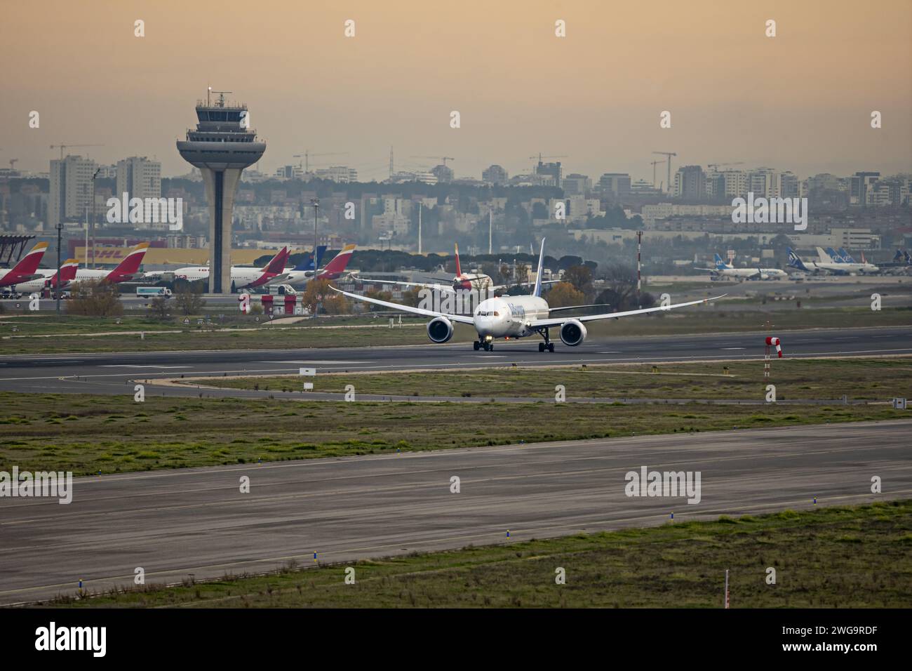 An airplane racing down the runway just before takeoff near the control tower Stock Photo