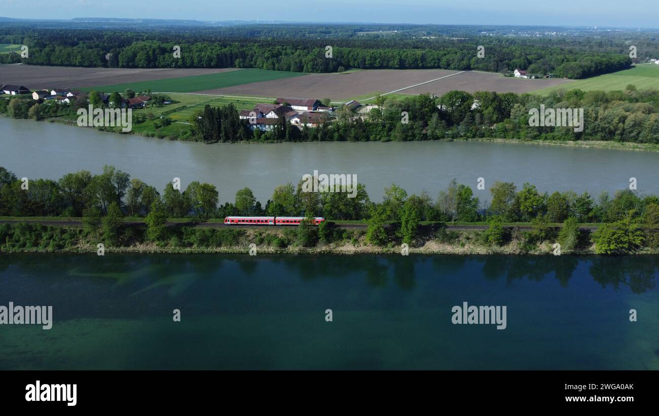 A red local railway runs on an embankment between two bodies of water with different colours, drone shot, Upper Bavaria, Bavaria, Germany Stock Photo
