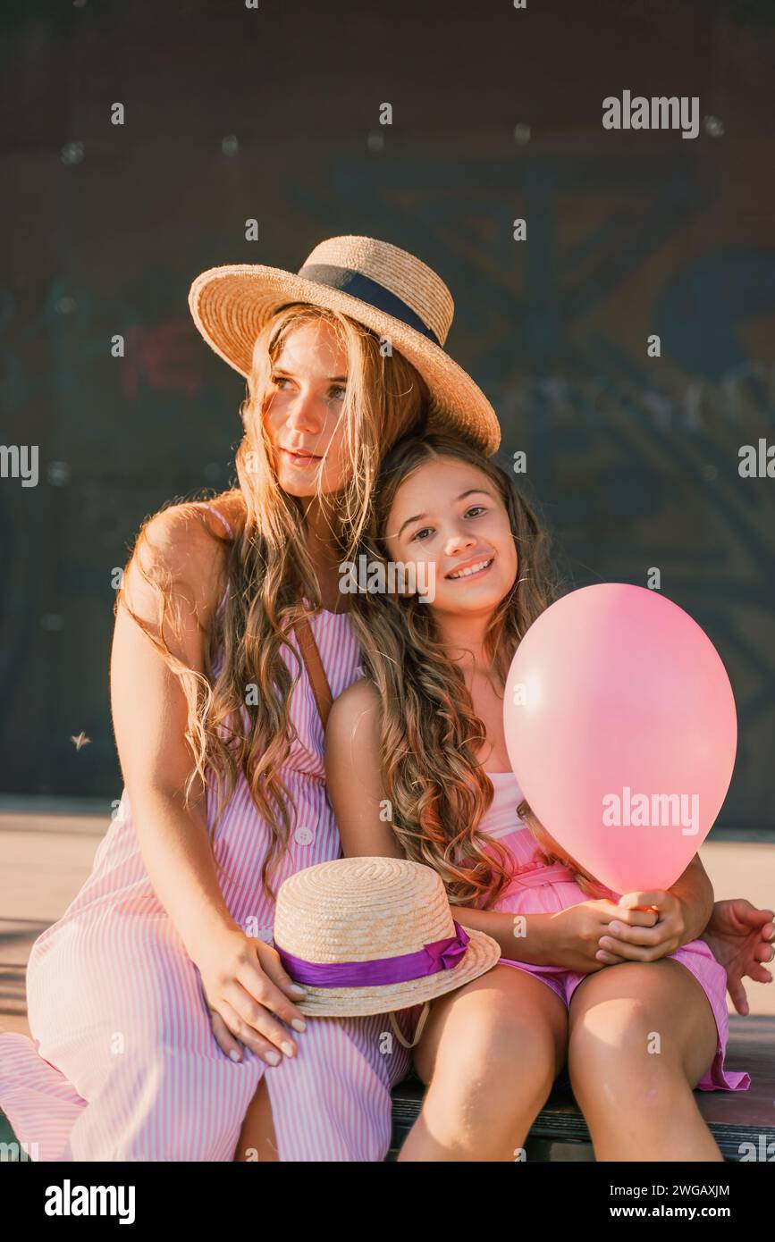 Portrait of mother and daughter in pink dresses with flowing long hair ...