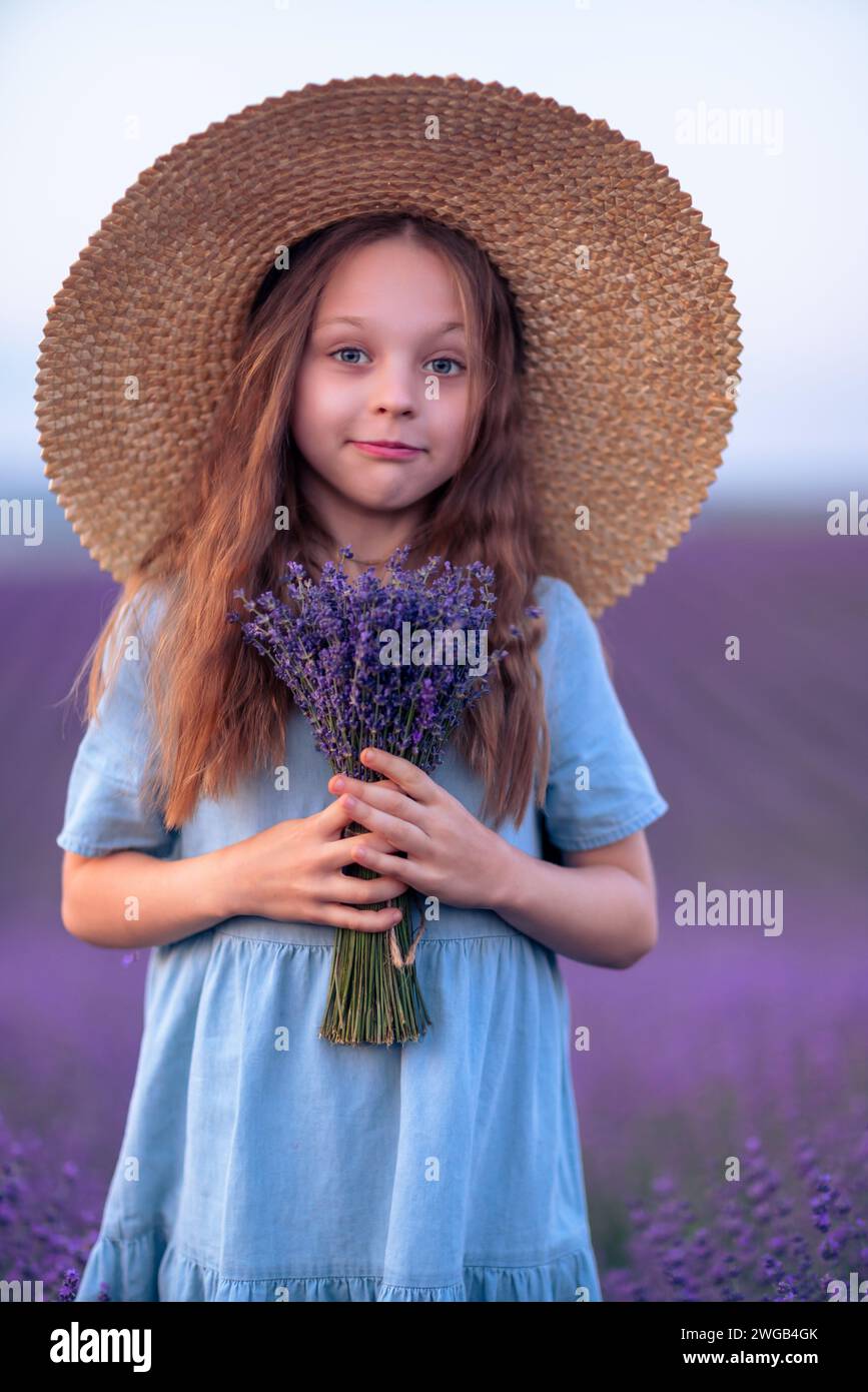 Girl lavender field in a blue dress with flowing hair in a hat stands ...