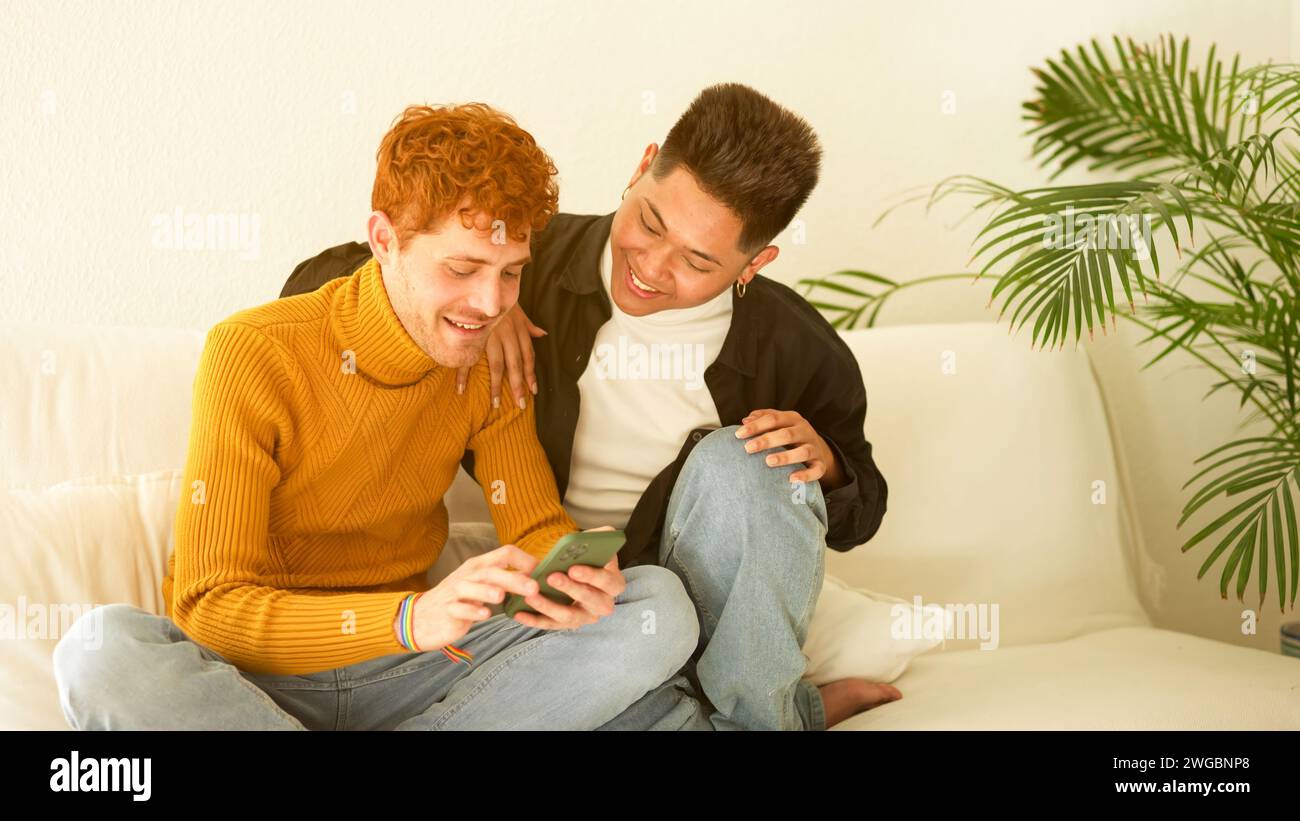 Gay couple smiling while using the mobile at home Stock Photo