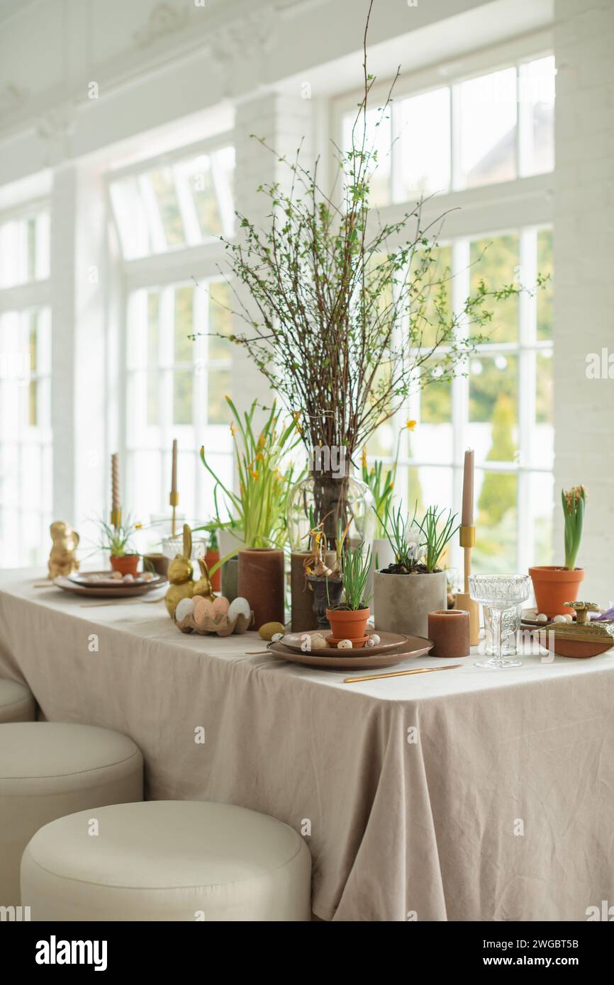 Festive Easter table setting with painted Easter eggs, spring flowers and candles Stock Photo