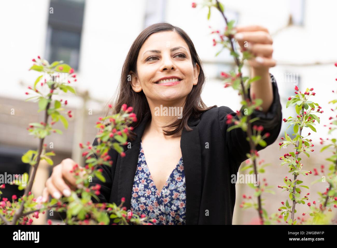 Smiling woman standing in her garden tending to her plants, Germany Stock Photo
