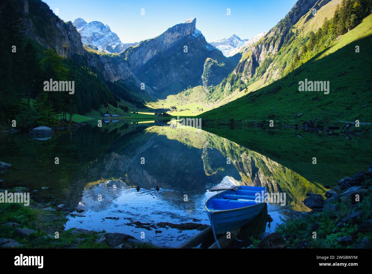 Boat moored in Seealpsee with mountain reflections in lake, Appenzell Innerrhoden, Switzerland Stock Photo