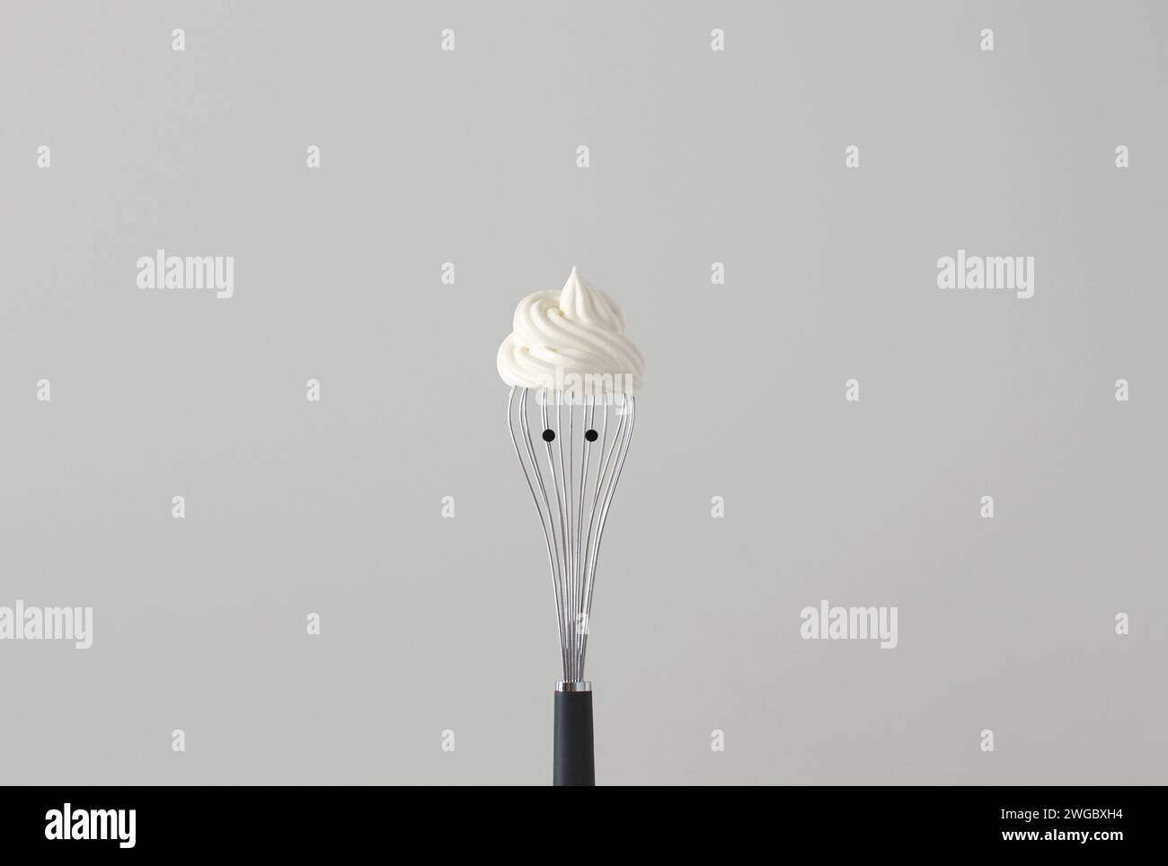 Conceptual portrait of a face with a cool hairstyle made from Whipped Cream On a Whisk With Black Dot Eyes Stock Photo