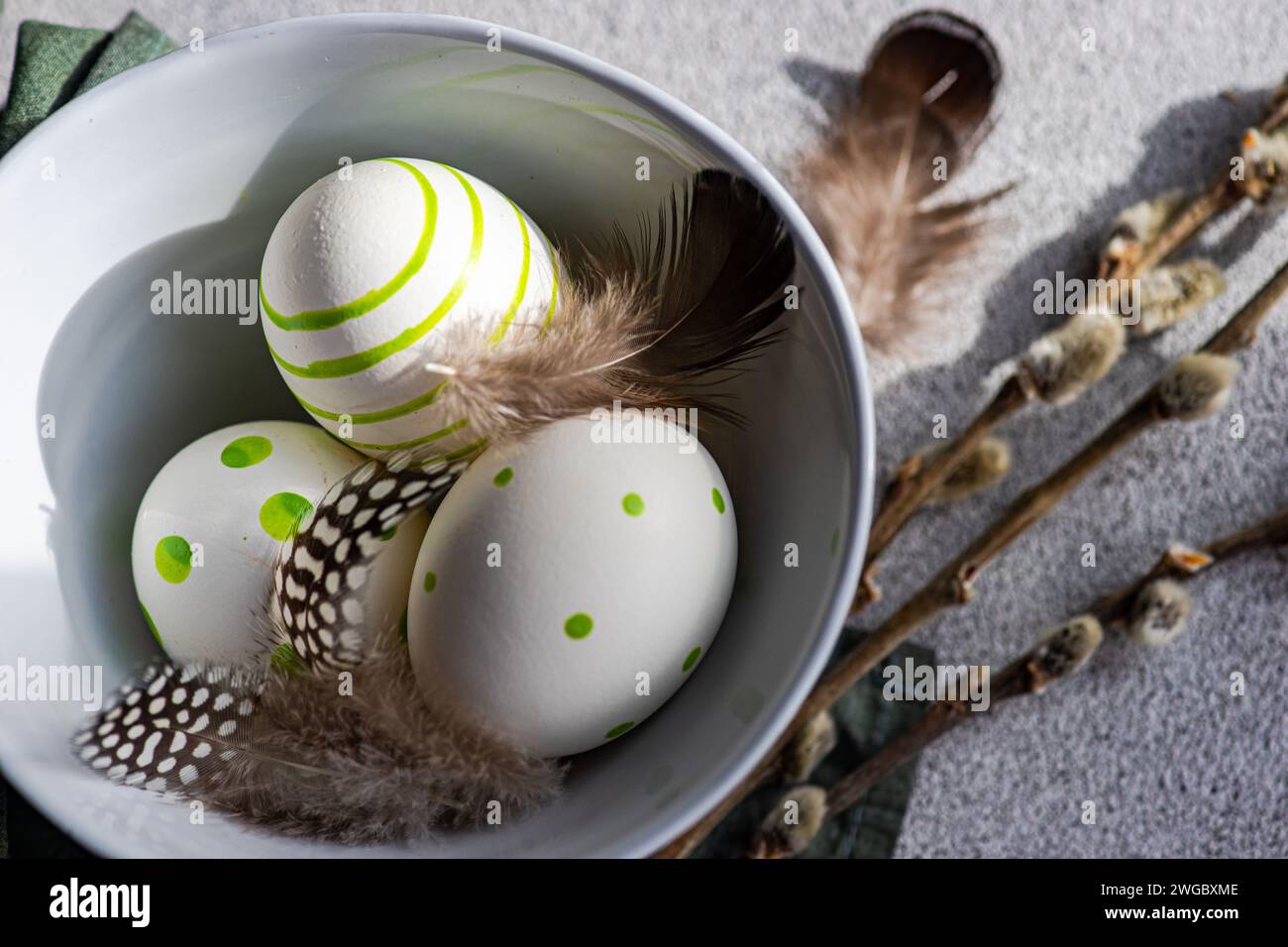 Overhead view of festive Easter arrangement with painted Easter Eggs, pussy willow branches and feathers in a bowl Stock Photo