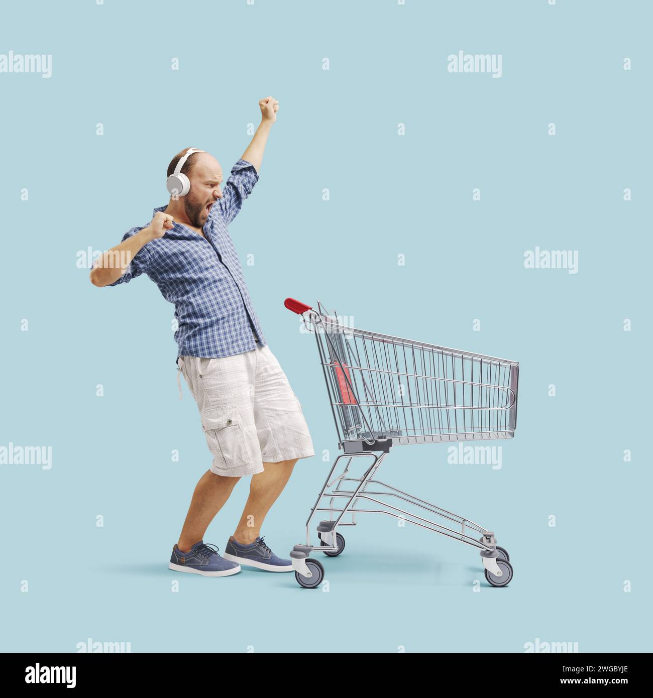 Excited man doing grocery shopping, he is listening to music and