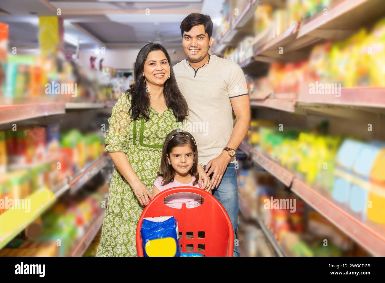 Portrait of Happy indian family of three shopping for groceries at the supermarket. Buying grocery for home. Stock Photo