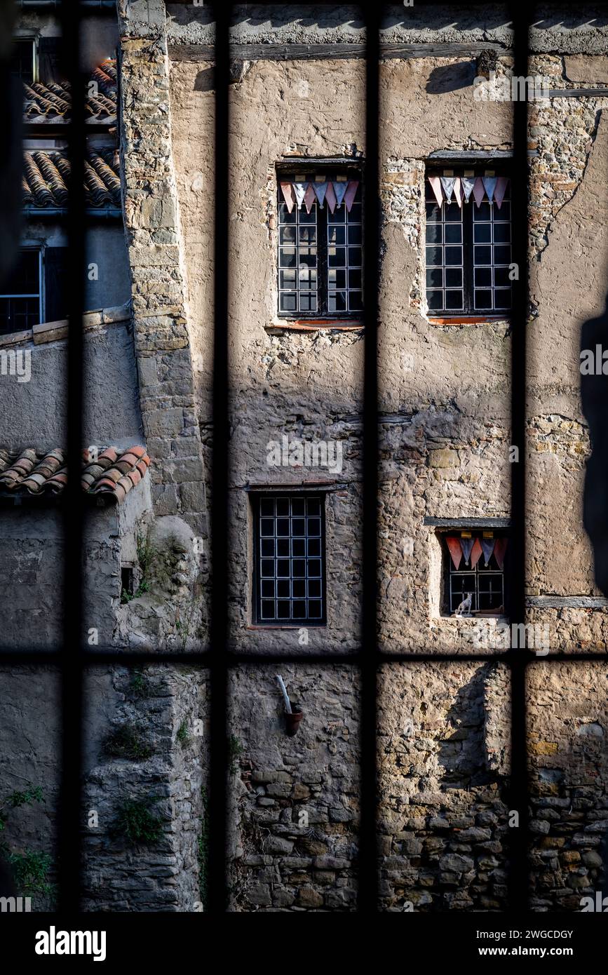 View of worn stone house through window bars of the opposite one, , Carcassonne, France Stock Photo