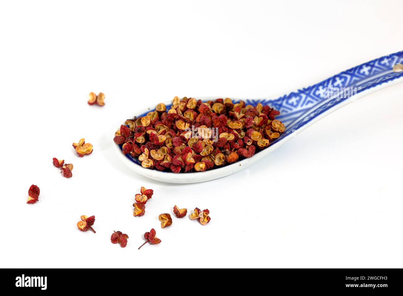 A soup spoon of dried Da Hong Pao Sichuan Peppercorns (Zanthoxylum bungeanum) 大紅袍 花椒 prickly ash berries isolated on a white background. Stock Photo