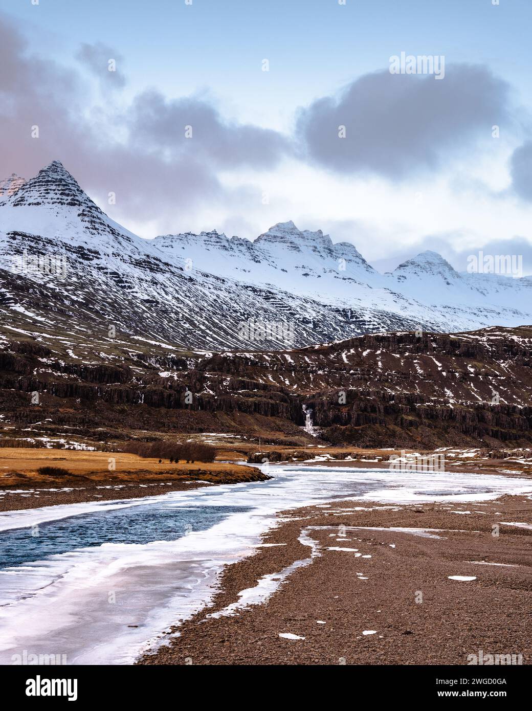 A scenic photo of southern Iceland with iced river in the foreground and mountains with snow in the background Stock Photo