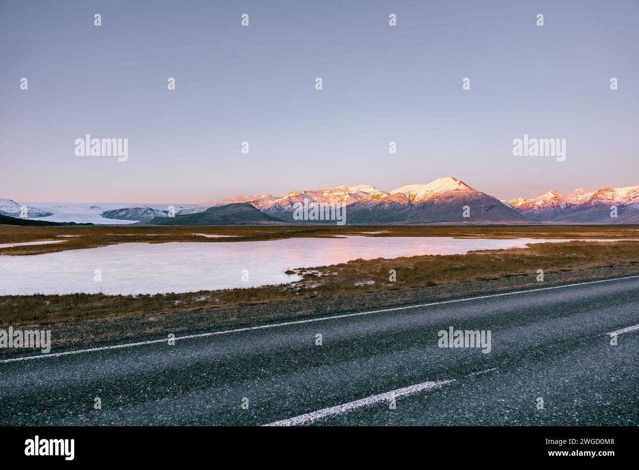 A landscape photo of southern Iceland with mountains and snow in the background, lots of ice in the foreground during sunset with a blue sky Stock Photo