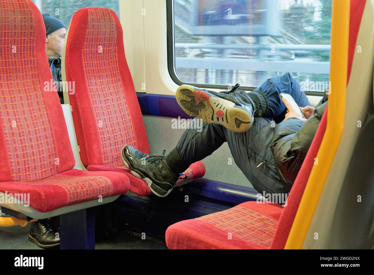 Close up of a male passenger on a suburban train with his foot resting on an empty seat Stock Photo