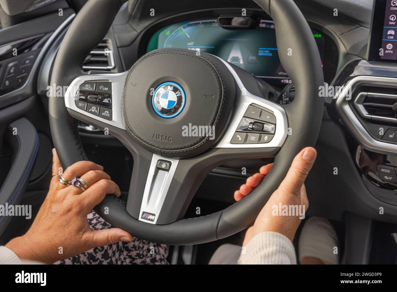 Closeup view of female hands on the steering wheel of the BMW iX3 M