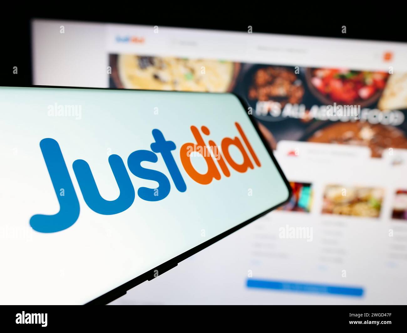 Mobile phone with logo of Indian technology company Just Dial Limited (Justdial) in front of website. Focus on center-left of phone display. Stock Photo