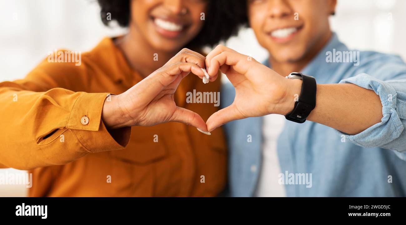 A close-up of a happy couple creating a heart shape with their hands ...