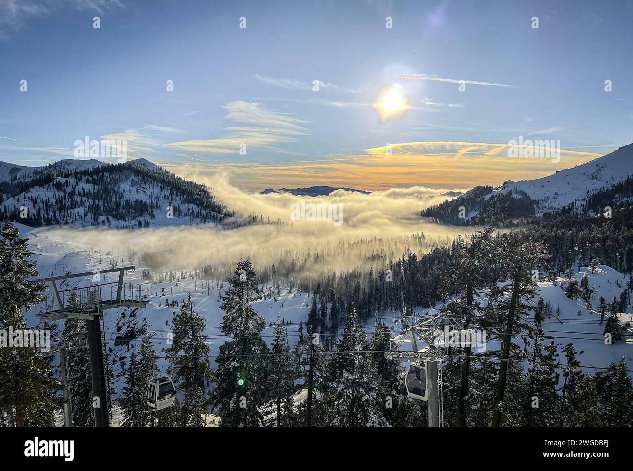 Some clouds moving low through trees on top of a snow-covered mountain in Lake Tahoe, California at sunset Stock Photo