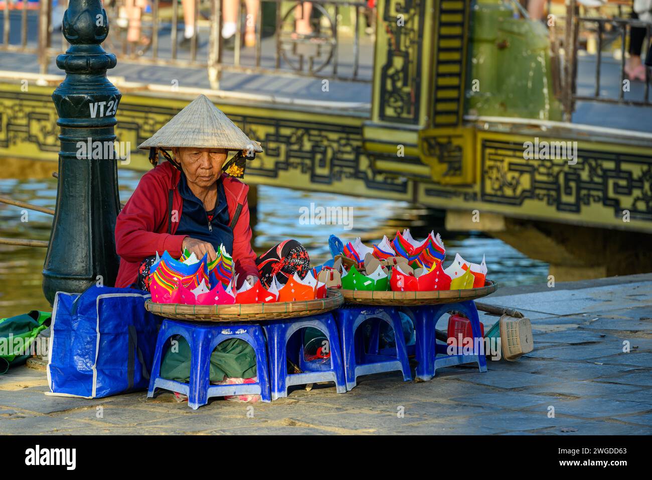 An elderly lady selling lanterns by the Thu Bon River, Hoi An, Vietnam Stock Photo