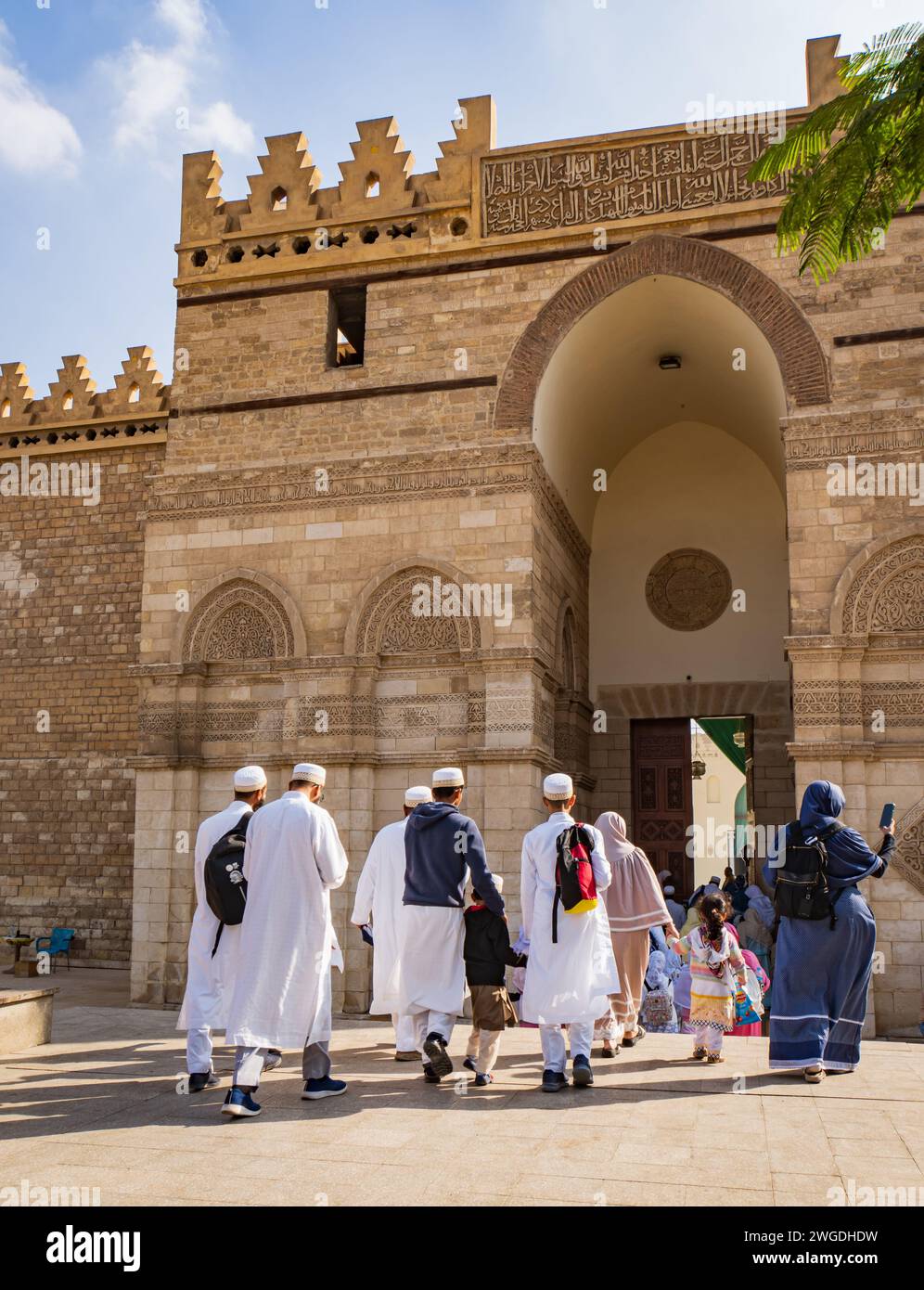 families in traditional dress entering the al-Aqmar Mosque on Moez Street in Fatamid or Medieval Cairo, Egypt Stock Photo
