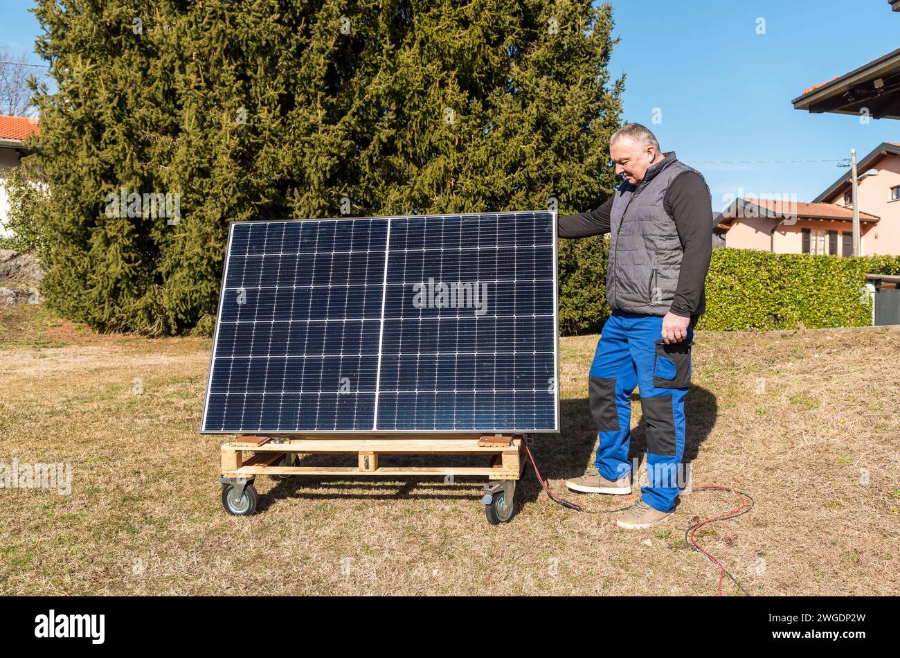 Mature man with photovoltaic solar panel in the garden. Stock Photo