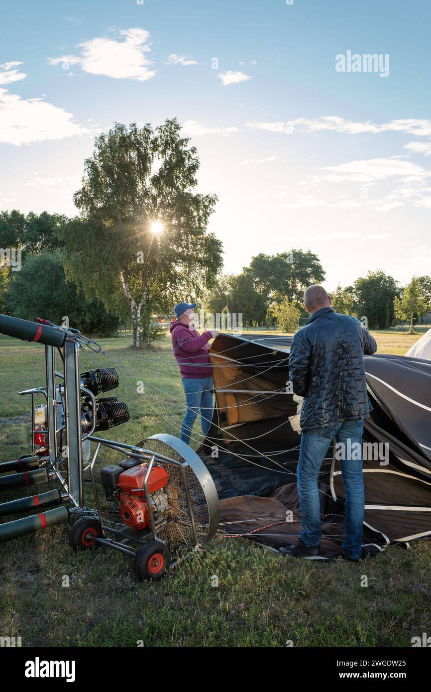 A balloon with a basket lies on the ground, equipment for filling the balloon with cold and hot air. Preparing the balloon for launch. Stock Photo