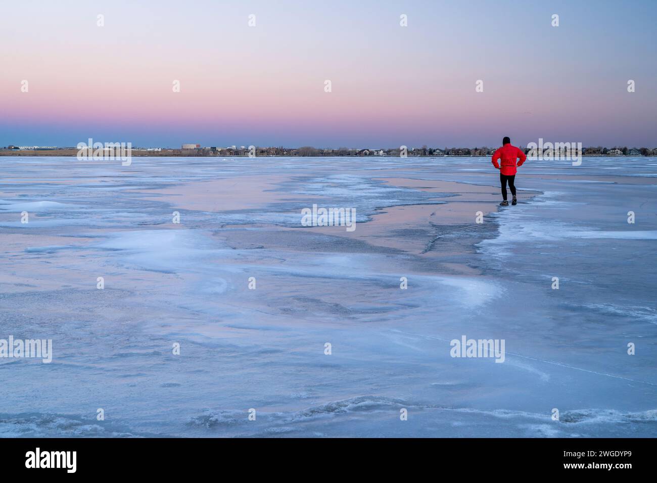 lonely male figure on a frozen lake at dusk in Colorado - Boyd Lake State Park Stock Photo