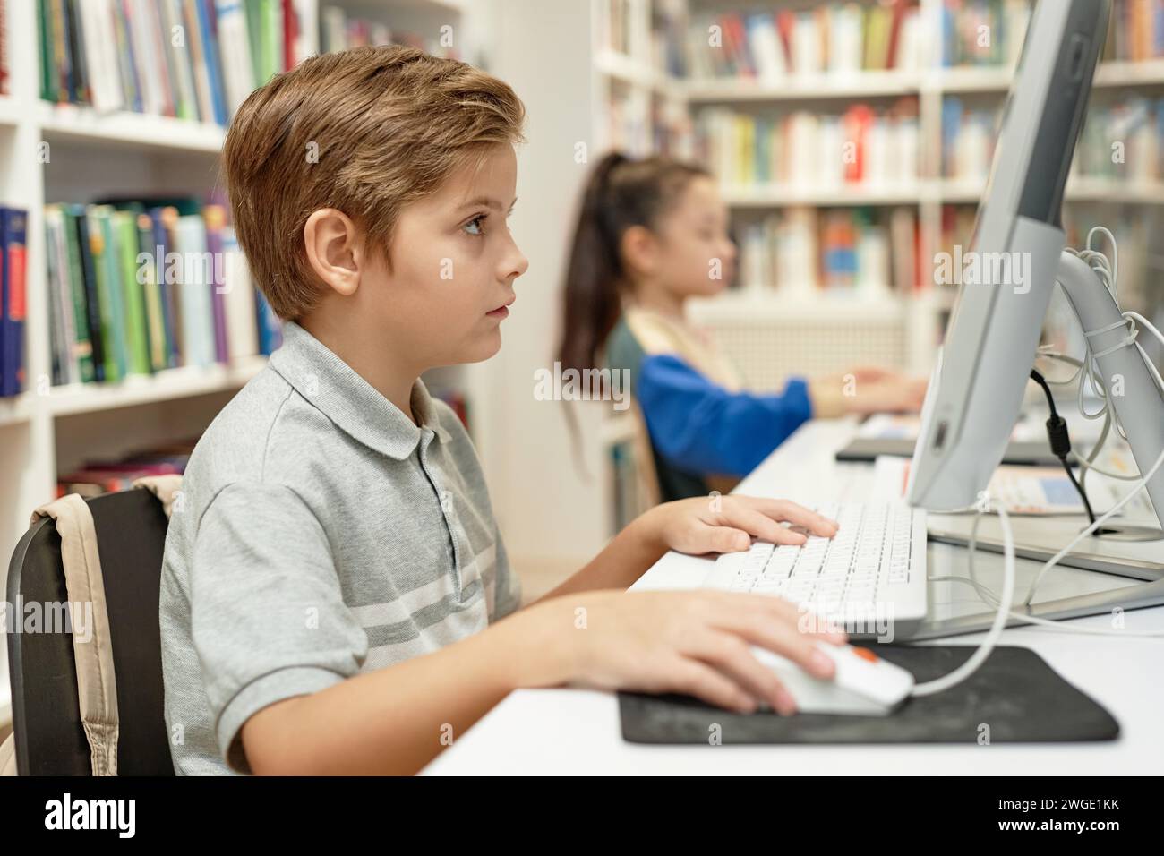 Side view portrait of serious young boy using PC computer in school ...