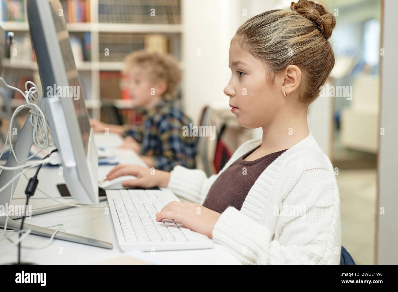 Side view portrait of serious young schoolgirl using computer in ...