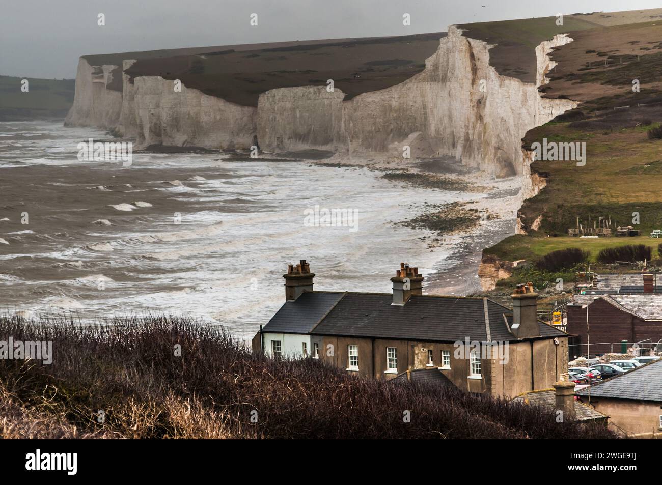 Birling Gap, Eastbourne, East Sussex, UK. 4th Feb, 2024. Erosion of the sedimentary chalk cliffs continues with numerous rock falls & new fissures appearing. The National Trust Visitor Centre cafe is being demolished (Centre Right in picture) & moved from the cliff edge to the front of the building. Of the 8 original terraced cottages, built in 1878, 5 remain, 3 having been demolished in 1973, 1994 & 2014 as the cliff edge moved closer. Credit: David Burr/Alamy Live News Stock Photo