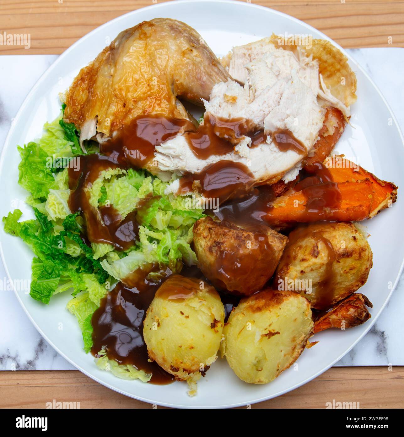 Roast chicken with roast potatoes savoy cabbage roasted chantenay carrots and gravy Stock Photo