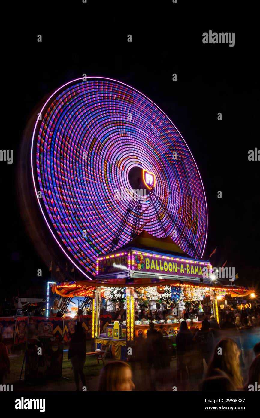 Dutch Wheel. Ferris Wheel. Carnival Ride with long exposure motion blur. Balloon-A-Rama carnival game tent in foreground. Canfield Fair, Mahoning Coun Stock Photo
