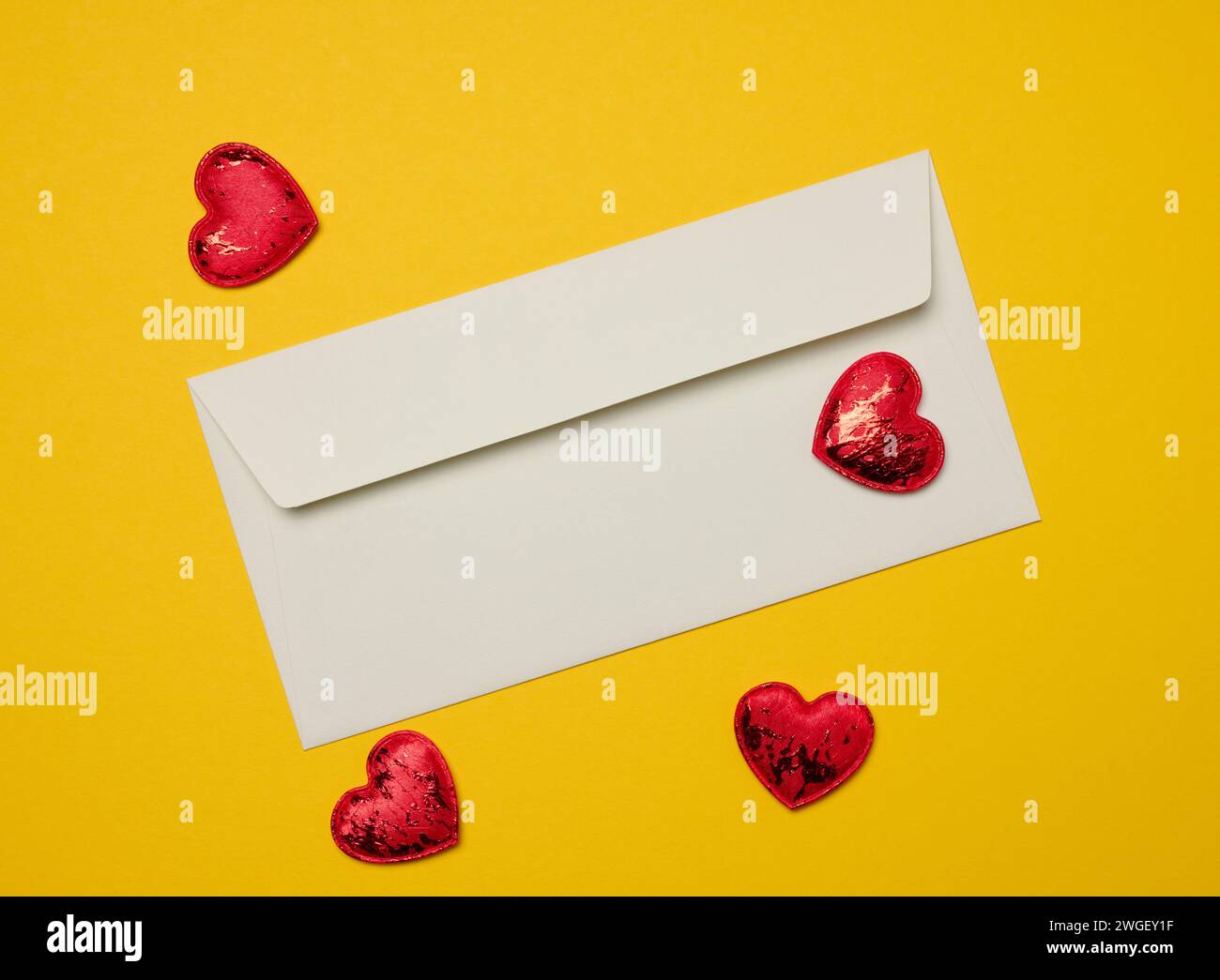 Rectangular white paper envelope and red hearts on a yellow background, holiday background Stock Photo