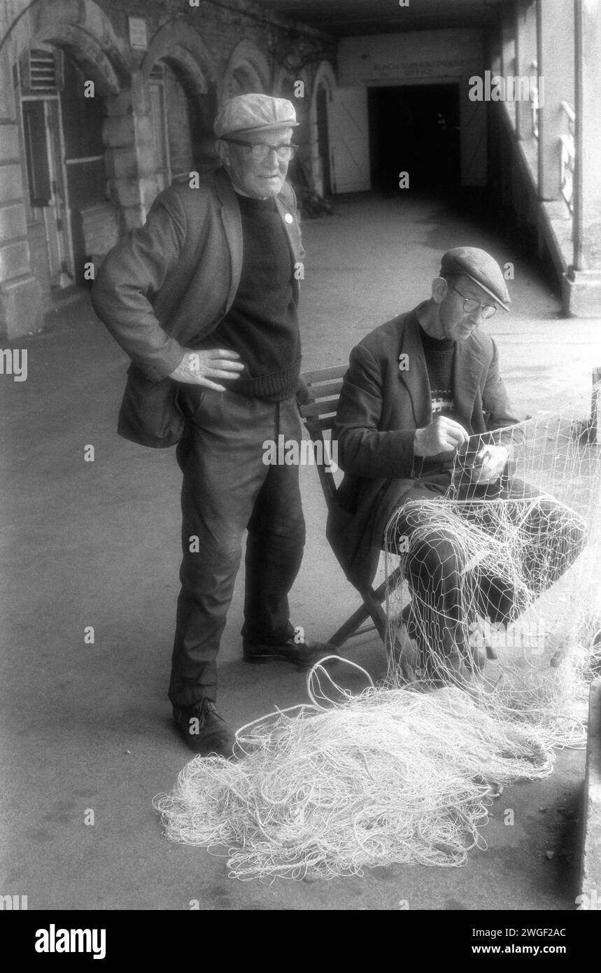 Brighton Beach 1970s UK.  Fishermen mending fishing nets. The Deep Sea Anglers Club, George Hillman mending the nets outside his archway workshop at the King’s Road Arches ( Now called the Artists Quarter) on Brighton beach. Brighton, East Sussex, England 1971. HOMER SYKES Stock Photo