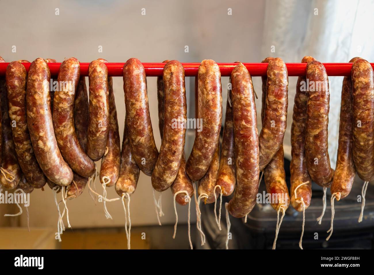 Traditional food. Raw sausages  hanging iand prepared to be smoked in a domestic smokehouse. Stock Photo