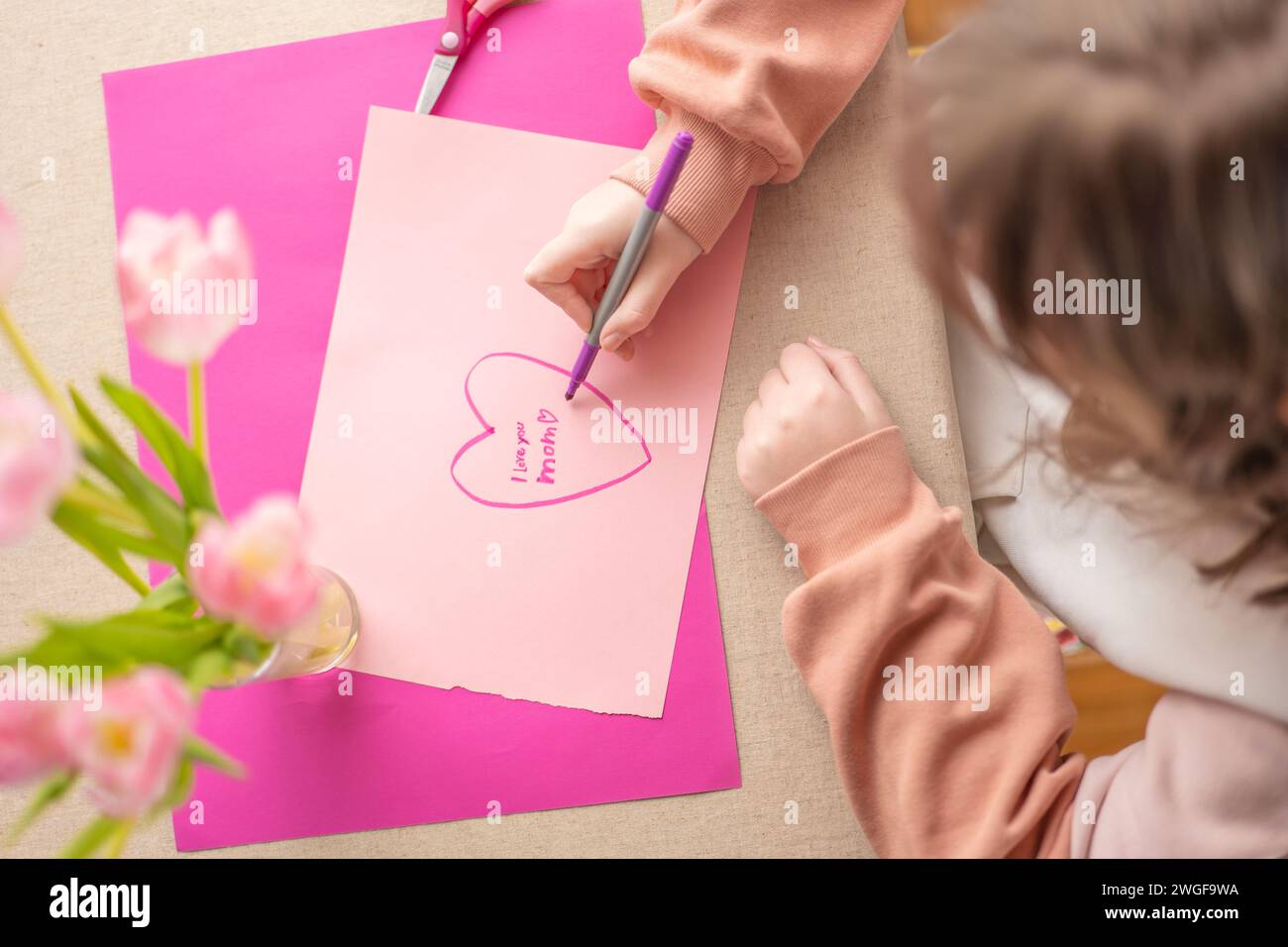 Mothers Day.Flowers and cards for mom.Daughter draws a card for mom.Message to mom.Child draws a heart and writes mom I love you. Stock Photo