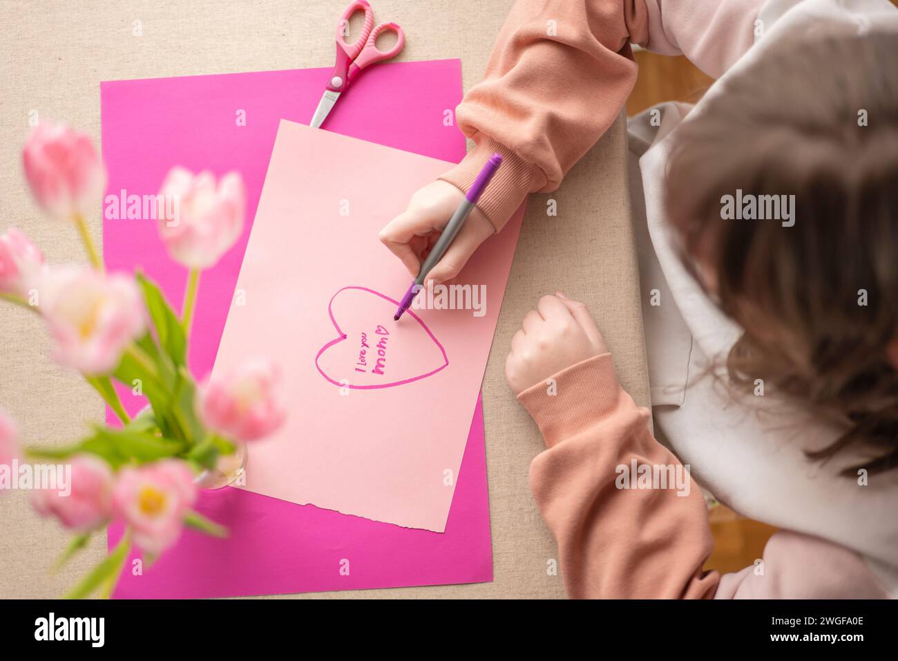 Mothers Day.daughter makes a card for his mother.Flowers and cards for mom.Daughter draws a card for mom.Message to mom.Child draws a heart and writes Stock Photo