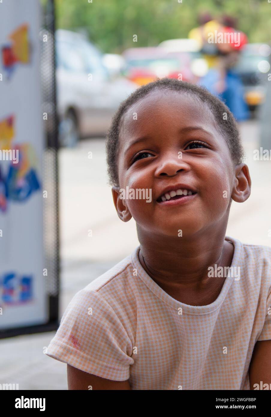 portrait of an african girl standing in the street, shopping mall parking with cars Stock Photo