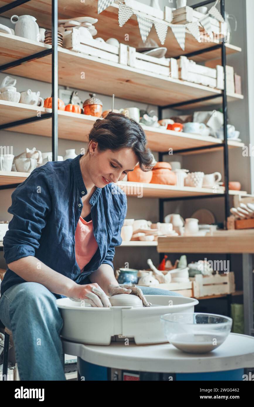 A woman ceramist at a pottery wheel in a workshop Stock Photo