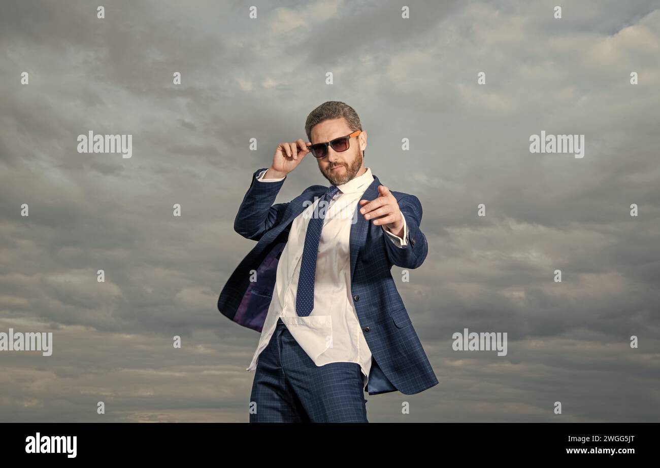 Businessman in sunglasses pointing finger straight. Businessman wearing