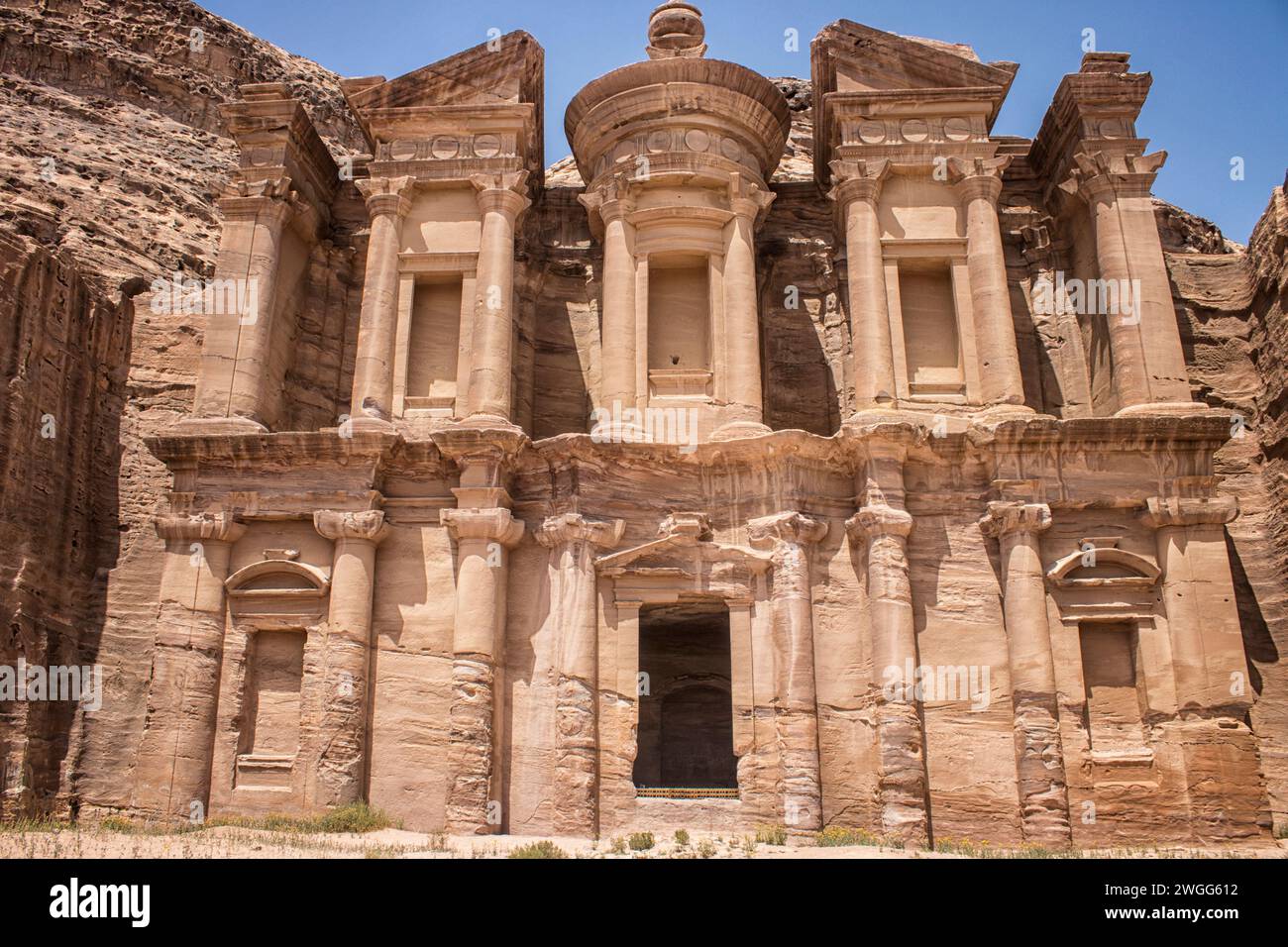 The facade of the Treasury at the UNESCO heritage site. Petra, is a historic and archaeological city in southern Jordan. Famous for its rock-cut architecture and water conduit system, Petra is also called the 'Rose City' because of the colour of the sandstone from which it is carved. It is adjacent to the mountain of Jabal Al-Madbah, in a basin surrounded by mountains forming the eastern flank of the Arabah valley running from the Dead Sea to the Gulf of Aqaba. Access to the city is through a famously picturesque gorge called the Siq, which leads directly to the Khazneh. Jordon. Stock Photo