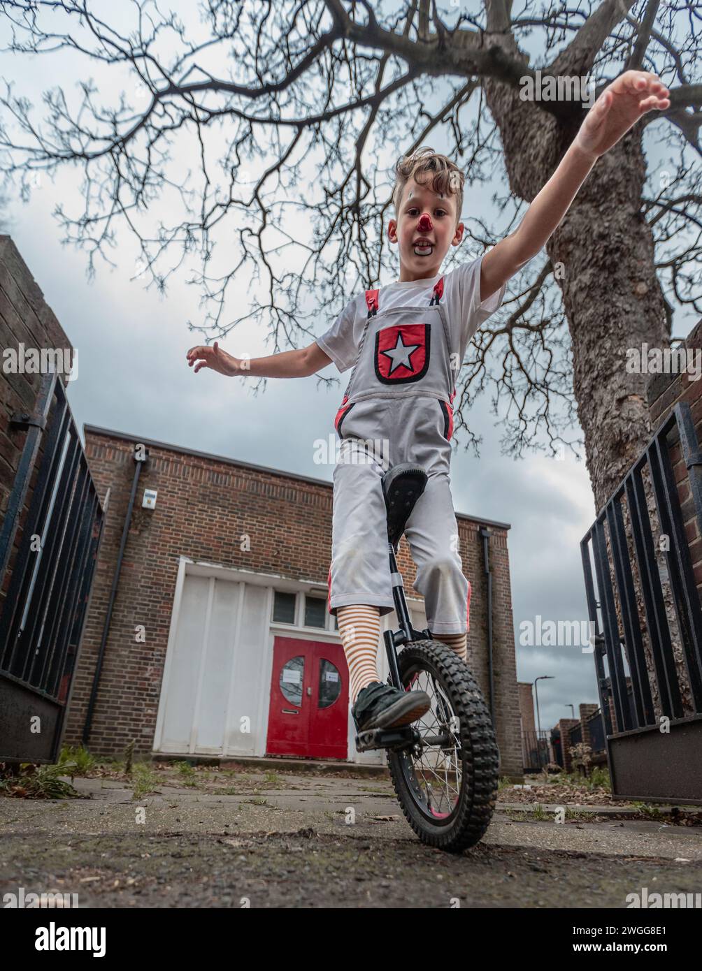 A young clown rides a unicycle at the Joseph Grimaldi event. Stock Photo