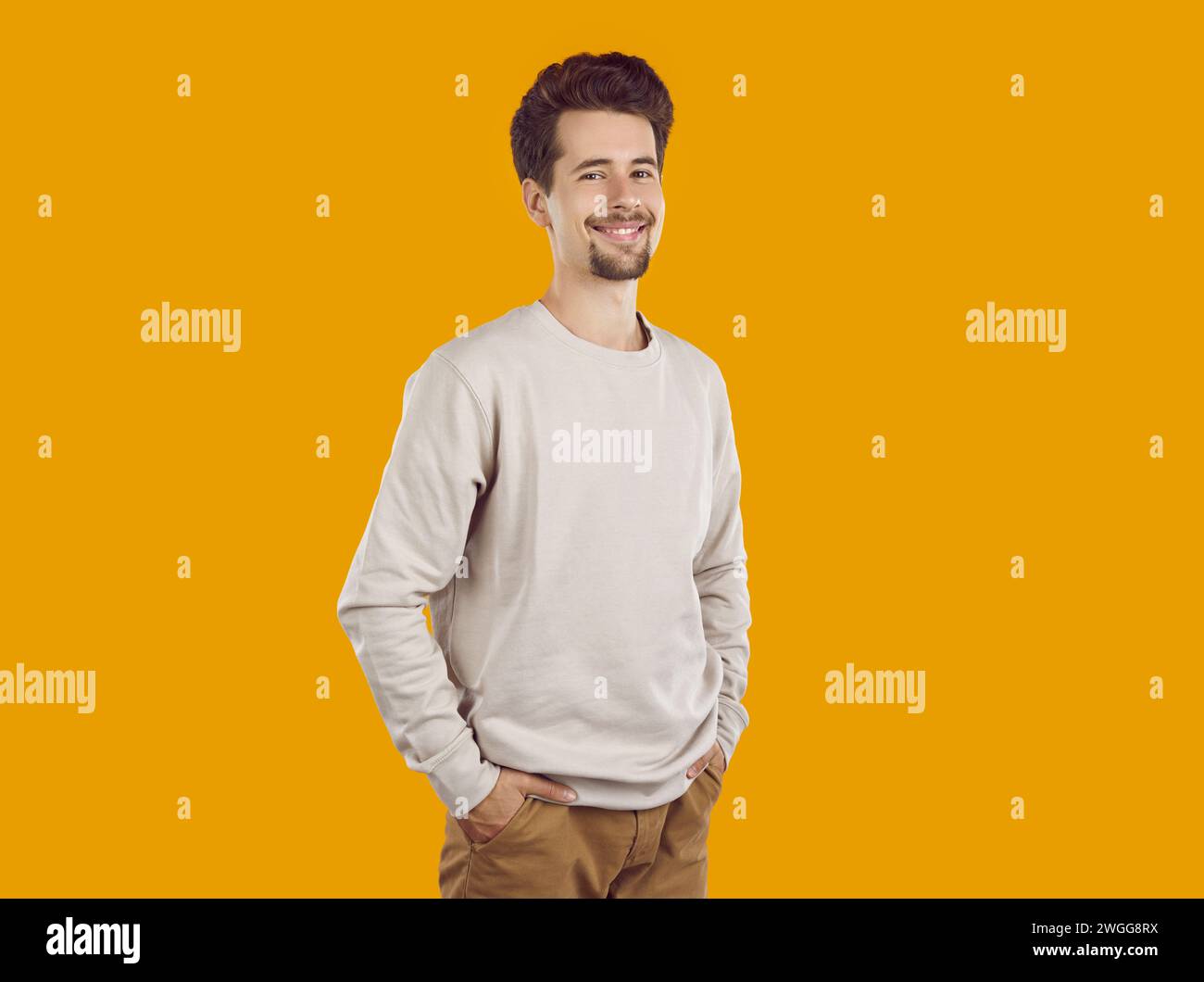 Confident handsome young man standing with his hands in pockets Stock Photo