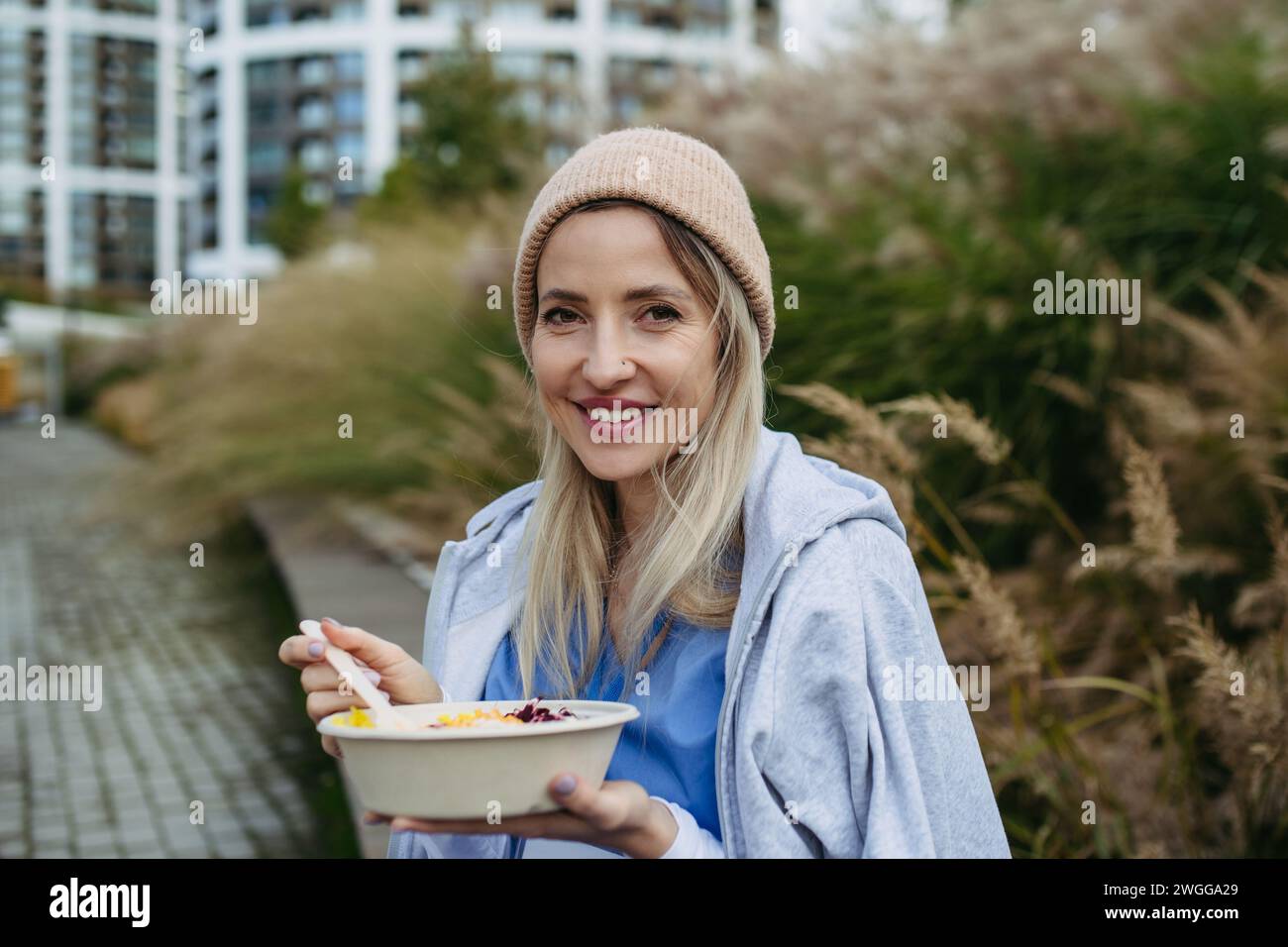 Nurse having healthy lunch, snack in front of hospital building, taking