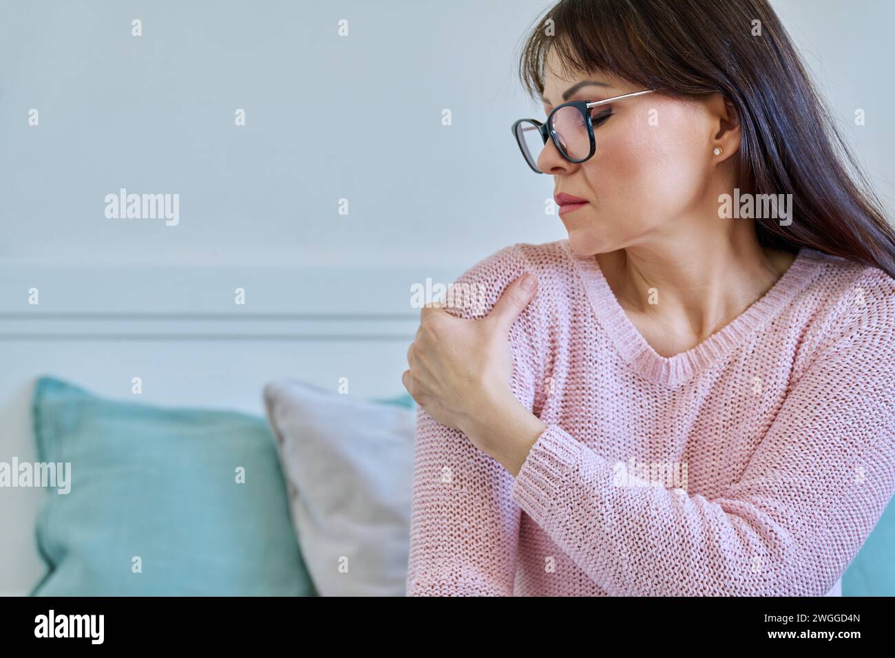 Middle-aged woman touching her sore shoulder joint Stock Photo - Alamy